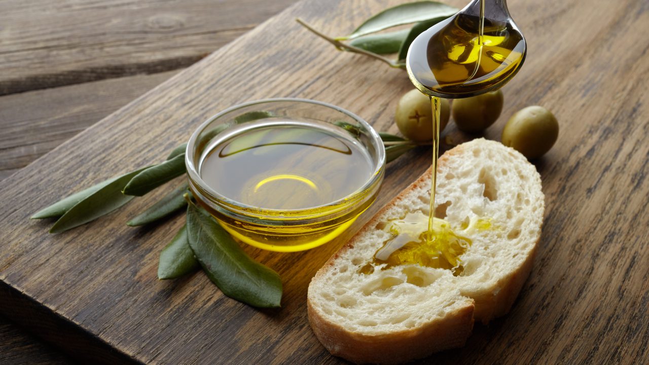 Olio d’oliva - slice of bread seasoned with olive oil on wooden table Olio d’oliva - slice of bread seasoned with olive oil on wooden table